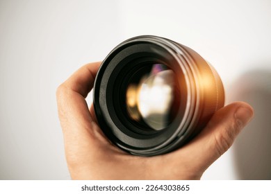 Banner of a photographic lens in a hand. Modern camera lens for a digital mirrorless camera. Professional photo gear
