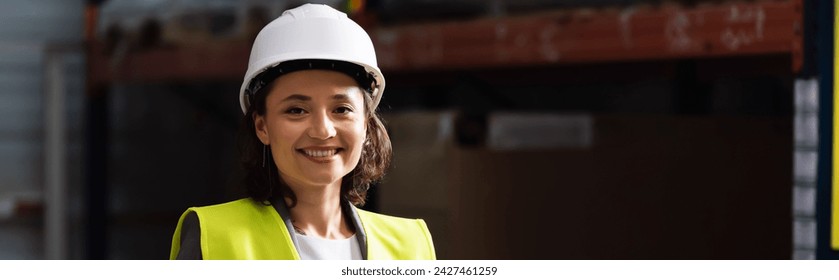 banner of professional woman in safety vest and hard hat standing with hands in pockets in warehouse - Powered by Shutterstock