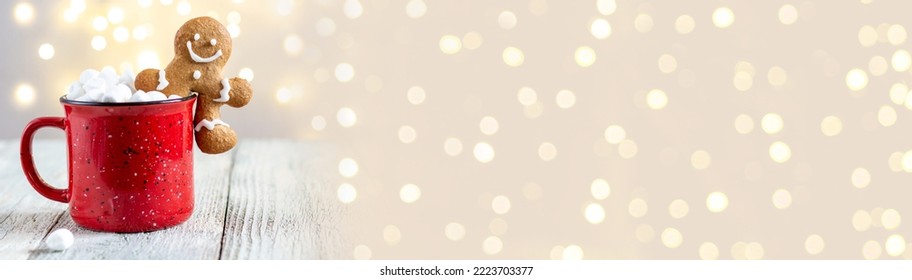 banner of a red cup of winter hot drink with marshmallows and gingerbread man on a white wooden background. Traditional Christmas atmosphere with bokeh. New year holiday concept. - Powered by Shutterstock