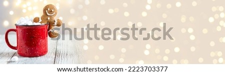 banner of a red cup of winter hot drink with marshmallows and gingerbread man on a white wooden background. Traditional Christmas atmosphere with bokeh. New year holiday concept.
