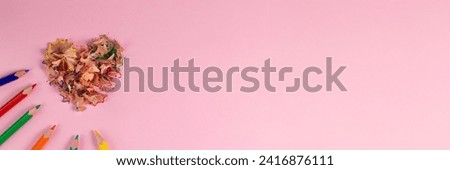 banner of sharpened colored pencils and heart-shaped pencil shavings on pastel pink color. Rainbow or LGBT pencils. Decoration for St. Valentine's Day. Top view