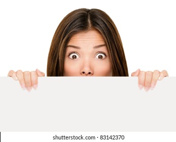 Banner Sign Woman Peeking Over Edge Of Blank Empty Paper Billboard With Copy Space For Text. Beautiful Asian Caucasian Woman Looking Surprised And Scared - Funny. Isolated On White Background.