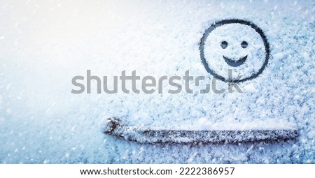 Banner of smiling face (symbol) painted on snow above windshield wiper of car. Winter, transport concept. Copy space. Empty place for your message.