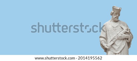 Banner with statue of a priest with figure of crucified Jesus in Vienna downtown at blue sky solid background with copy space, Austria, details, closeup. Concept of historical architecture heritage