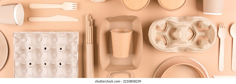 Banner. Sustainable Paper Packaging For Food Industry - Paper Utensils, Cups, Plates, Drinking Straws, Egg Boxes And Food Containers Over Light Brown Background. Flat Lay