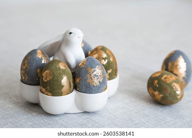The banner. Table setting. An egg stand with a rabbit, and Easter eggs with gilding on a linen tablecloth. The concept of a bright Easter holiday.
