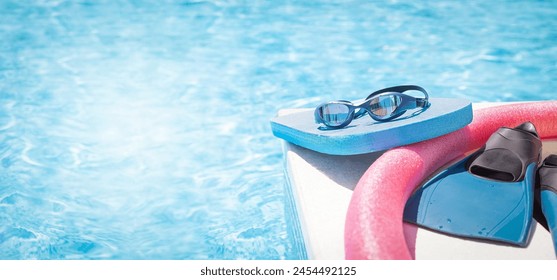 Banner for teaching  professional swimming. Sport goggles, pool board, swim noodles and fins for swimming are near swimming pool. Healthy, active lifestyle. Copy space. Empty space for your messeges. - Powered by Shutterstock