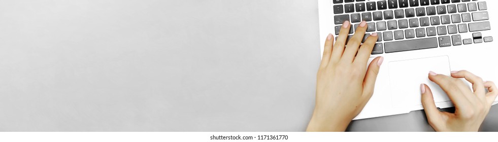 Banner of top view laptop keyboard and female hands with copyspace in grey color background. Concept of blog header and business advertisement.