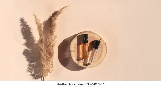 Banner Of Two Perfume Samples With Yellow Liquid On Wooden Tray On Beige Background With Pampas Grass. Luxury And Natural Cosmetics Presentation. Tester On Woodcut In The Sunlight. Shades And Lights