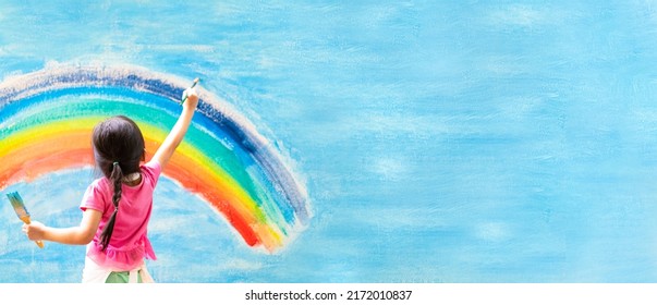 Banner unidentified little girl is painting the colorful rainbow   sky the wall   she look happy   funny  concept art education   learn through play activity for kid development 