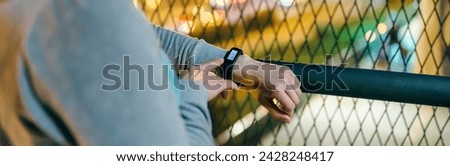 Banner of unrecognizable female hand touching digital wrist band screen to check daily step counter after walking at night on town. Woman athlete looking run summary on smart sport watch on evening.