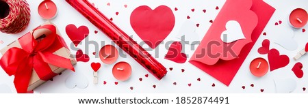 Banner. Valentine's Day. Flat lay of red hearts, handmade gift boxes, red roses and a notebook for writing on a white background. Copy space. The concept of holidays and love.