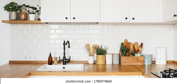 Banner Ansicht auf weißer Küche im skandinavischen, modernen Stil, Küchendetails, Pflanzen auf Holztisch, weißer Keramikziegelwand. Nachhaltig lebende, umweltfreundliche Küche.