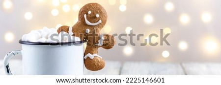 banner of a white cup of winter hot drink with marshmallows and gingerbread man on a white wooden background. Festive xmas background. Traditional Christmas atmosphere with bokeh.