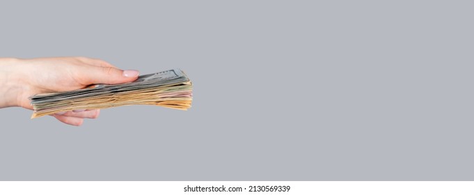 Banner With Woman Hand Holding Dollar Bills Stack On Grey Background. American Money And Finance Concept. Copyspace. High Quality Photo