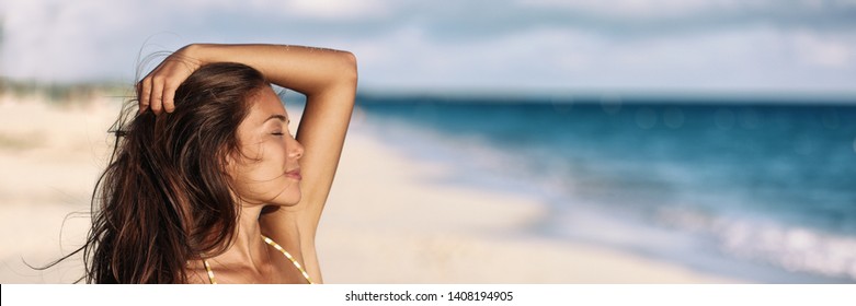 Banner woman relaxing touching her hair wellness summer holiday ocean beach panoramic background on tropical Caribbean summer vacation panorama. Asian girl breathing clean air. - Powered by Shutterstock