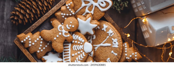 Banner. Wooden box with homemade delicious gingerbread cookies decorated with white icing. Handmade zero waste gift for Christmas or New Year. Cozy home atmosphere, fairy lights, fir tree branches - Powered by Shutterstock