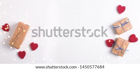 Banner with wrapped boxes with presents and  little red hearts on white textured background. Place for text.  Flat lay.