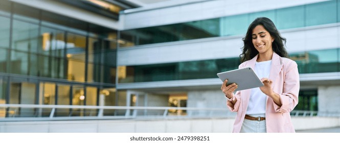 Banner of young middle eastern Israel businesswoman using tablet pc application for online remote work at office business building outdoors. Indian or arabic woman holding digital computer. Copy space - Powered by Shutterstock