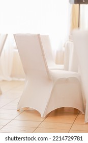 Banquet chairs covered with white cloth arranged in the row preparing for the ceremony reception