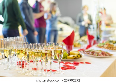 Banquet Event. Table With The Wineglasses, Snacks And Cocktails. People Celebrating In The Background.