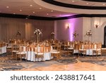 A banquet hall with tables and chairs set up for a wedding reception.