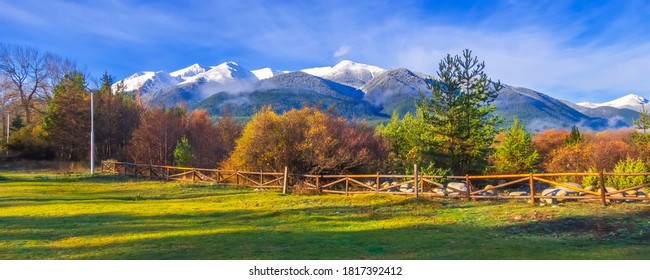 Bansko, Bulgaria autumn banner landscape with wooden fence, colorful trees, Pirin mountains snow peaks