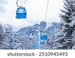 Bansko, Bulgaria winter ski resort panorama with blue gondola lift cabins, snow forest pine trees, mountain peaks slopes view