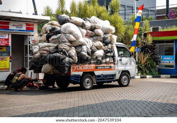 Banten, Indonesia. An overload pickup car carrying\
piles of filled sacks is seen to have its rear tire fixed, on a hot\
sunny day of August\
2021.