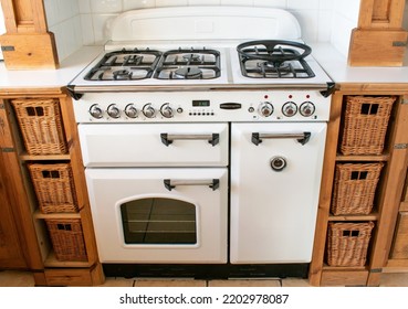 Banwell, North Somerset, UK. September 16th 2022. White And Black Rangemaster Stove Type Cooker With Wooden Cabinets On Either Side. White Tiled Clean Background. Food Preparation In A Clean Setting.