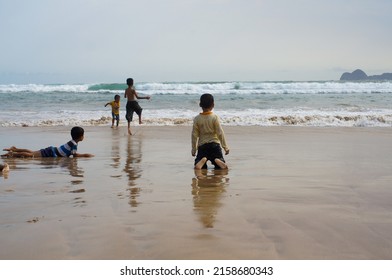 Banyuwangi City, Indonesia. July 31, 2014. Children Are Playing On The Red Beach Of Banyuwangi With Views Of The Beach, Clean Sand, Mountains, And A Collection Of Blue Clouds.