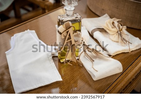 Baptism Ceremony Essentials: Elegant Set with Decorated Oil Bottle and White Underwear Ensemble. Ideal for use in religious ceremonies, cultural events, and editorial features. Selective focus.