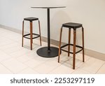 Bar chairs and round table in cafe. Round coffee table with steel base and two tall stools. Tall table steel legs simplistic, tall wooden bar stools. Nobody, selective focus