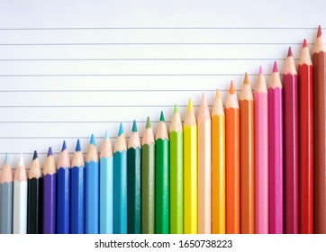 Bar Chart Graph Rainbow Of Colored Pencils Slide Up Against A Sheet Of Lined Paper Sloping In A Good Direction Of Success