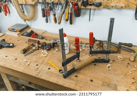 Bar clamps joining two wooden pieces together using glue in a woodworking studio. High quality photo