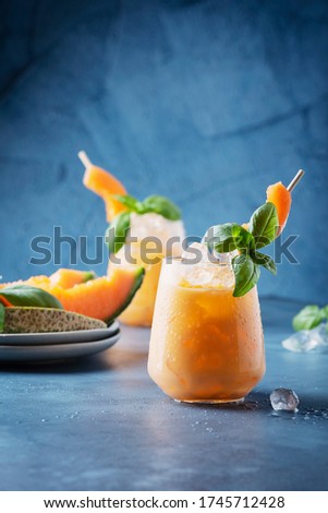 Bar concept. Sweet summer liquor with melon, ice and basil on blue background. Selective focus image with copy space for your text