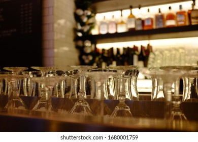 Bar With Glasses Turned Upside Down, Bottles Of Alcohol In The Background.