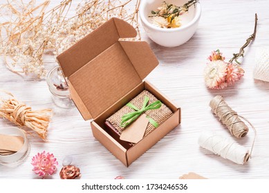 Bar of homemade soap wrapped in hemp fabric on wood background