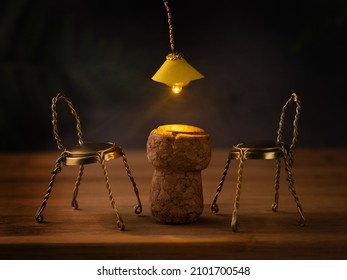 Bar mood, smoky, dark background, plank floor. The table is made of champagne cork, but the chairs are made of metal parts of cork. A yellow chandelier shines above the table. Sense photo. Mood. - Shutterstock ID 2101700548