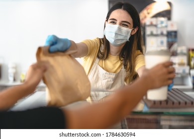 Bar owner working only with take away orders during corona virus outbreak - Young woman worker wearing face surgical mask giving takeout meal to customers - Healthcare and Food drink concept  - Shutterstock ID 1784630594