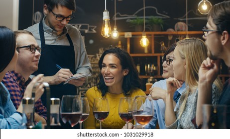 In the Bar/ Restaurant Waiter Takes Order From a Diverse Group of Friends. Beautiful People Drink Wine and Have Good Time in this Stylish Place.