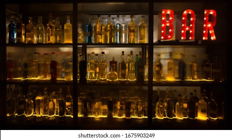 BAR sign with lights in the dark with bottles of alcohol. 