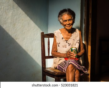 Baracoa, Cuba On January 7, 2016: In A Cuban House An Old Woman Is Enjoying A Beer In The Sun