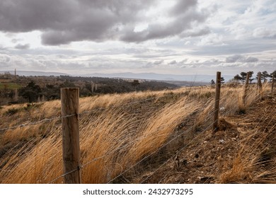 barb wire fence over the hill autumn yellow grass cloudy sky