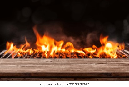 barbecue BBQ grill with flaming fire and ember charcoal on black background, wooden table - Shutterstock ID 2313078047