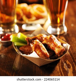 barbecue buffalo chicken wings served with beer, celery, and ranch in basket