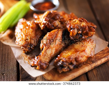 barbecue chicken wings close up on wooden tray shot with selective focus