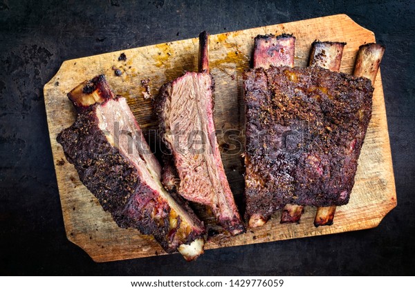 Barbecue chuck beef ribs with hot rub as top view\
sliced on a wooden cutting board\
