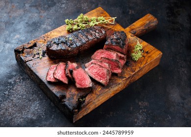 Barbecue dry aged angus roast beef steak with herb butter and dried oregano served as close-up on a rustic cutting board with copy space  - Powered by Shutterstock