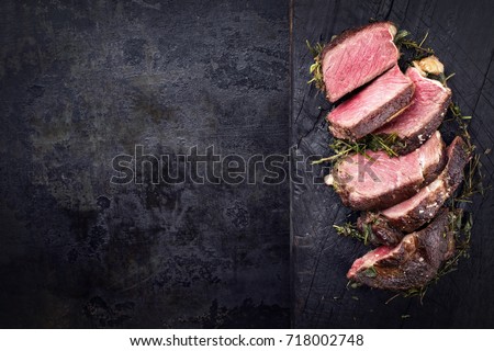 Barbecue dry aged Kobe rib eye steak as close-up on a burnt board with copy space left 